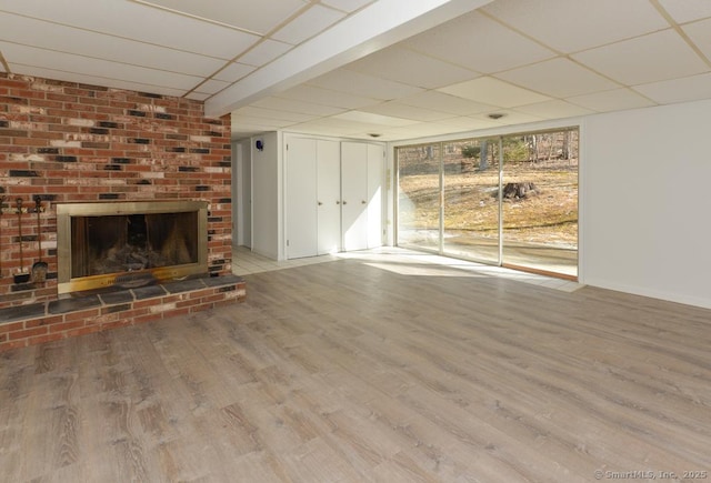 unfurnished living room featuring a drop ceiling, a fireplace, and wood finished floors