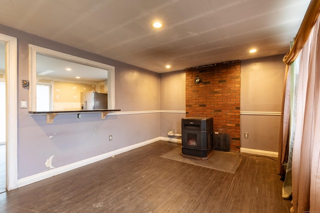 unfurnished living room featuring a wood stove, baseboards, wood finished floors, and recessed lighting