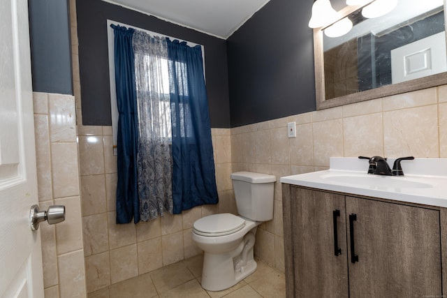 half bathroom featuring tile walls, toilet, wainscoting, vanity, and tile patterned flooring