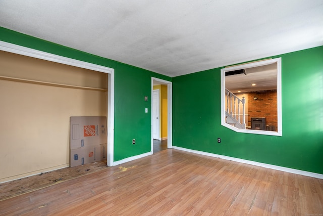 unfurnished bedroom featuring a fireplace, wood finished floors, and baseboards