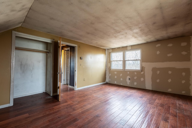 unfurnished bedroom featuring a closet, wood-type flooring, vaulted ceiling, and baseboards