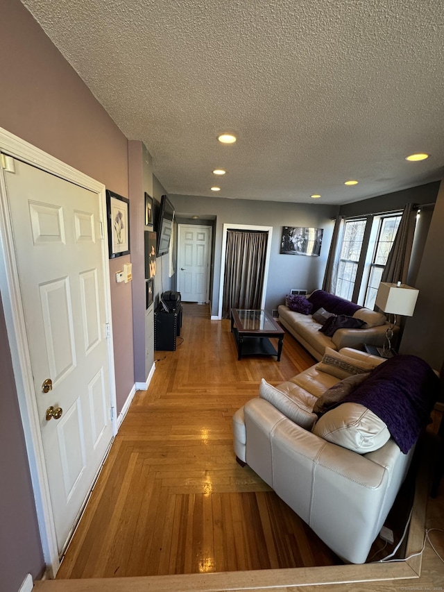 living room with parquet flooring, baseboards, a textured ceiling, and recessed lighting