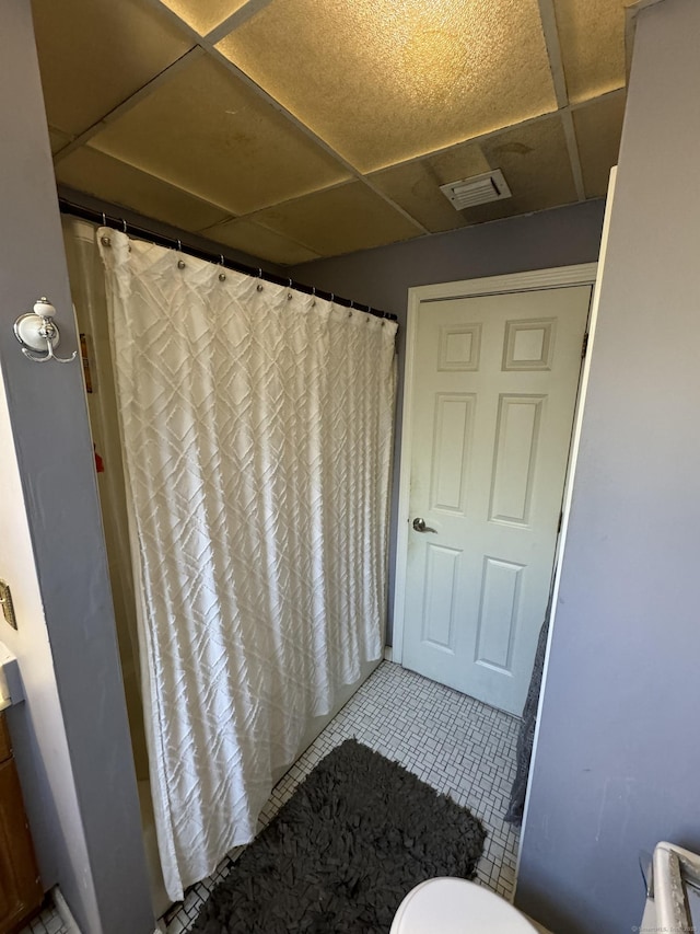 bathroom with visible vents, toilet, curtained shower, tile patterned flooring, and a paneled ceiling