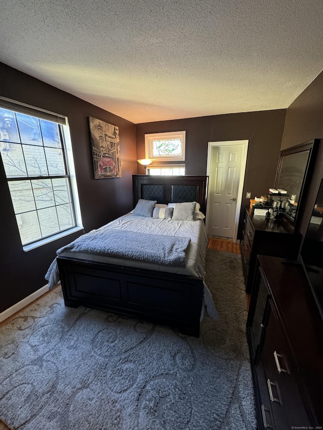 bedroom with a textured ceiling, carpet flooring, and baseboards