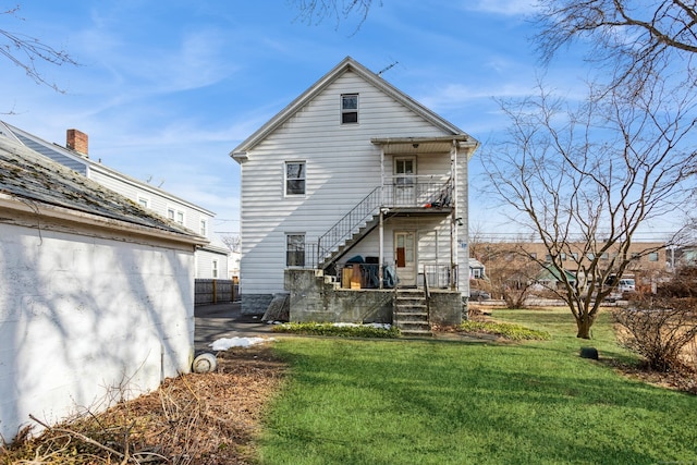 rear view of property featuring stairs and a lawn