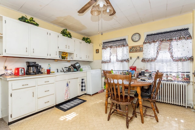 kitchen with washer / clothes dryer, light countertops, radiator heating unit, a ceiling fan, and white cabinetry