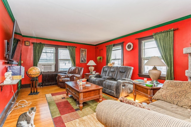 living area with a healthy amount of sunlight, radiator heating unit, cooling unit, and wood finished floors