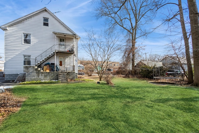 rear view of property featuring stairs and a yard