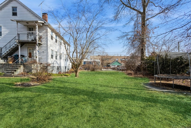 view of yard featuring a trampoline and stairway