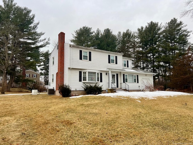 view of front facade featuring a front lawn, a chimney, and central AC unit