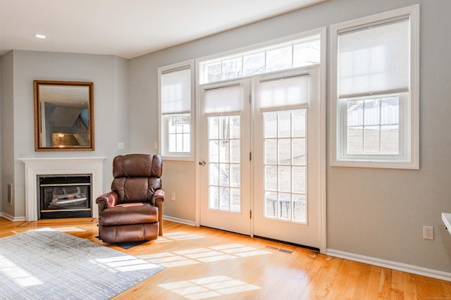 sitting room featuring baseboards, visible vents, a glass covered fireplace, light wood-style floors, and recessed lighting