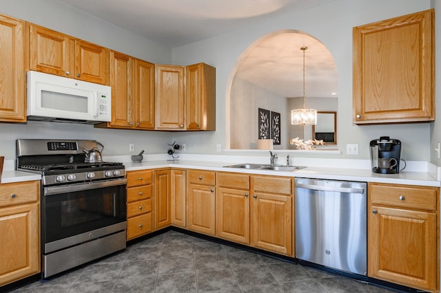 kitchen with stainless steel appliances, dark tile patterned flooring, light countertops, and a sink