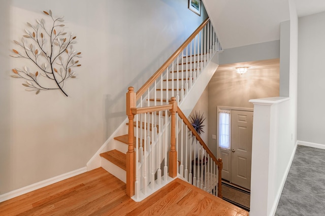 stairs with a high ceiling, baseboards, and wood finished floors