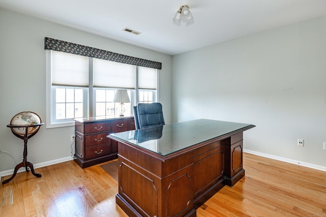 home office with baseboards, a healthy amount of sunlight, visible vents, and light wood-style floors