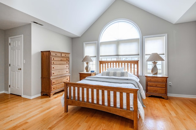 bedroom with lofted ceiling, baseboards, visible vents, and light wood finished floors