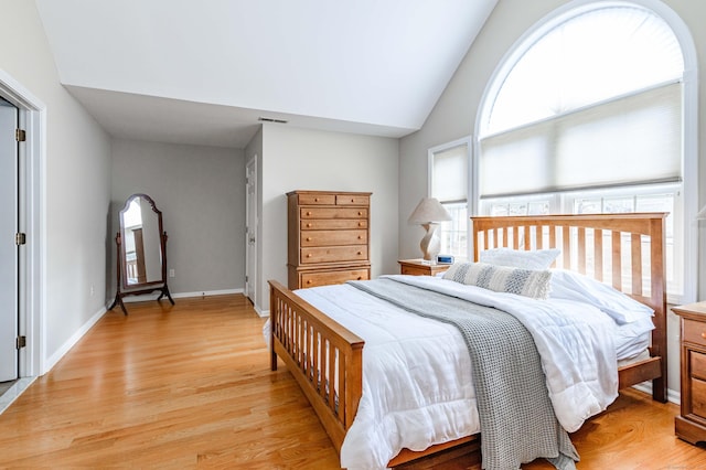 bedroom featuring vaulted ceiling, light wood finished floors, visible vents, and baseboards