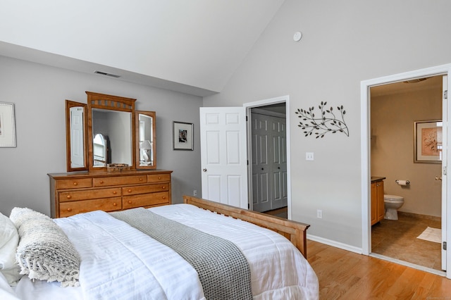 bedroom with visible vents, light wood-style floors, ensuite bath, high vaulted ceiling, and baseboards