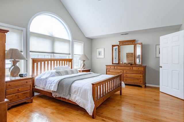 bedroom with high vaulted ceiling, light wood-type flooring, and visible vents