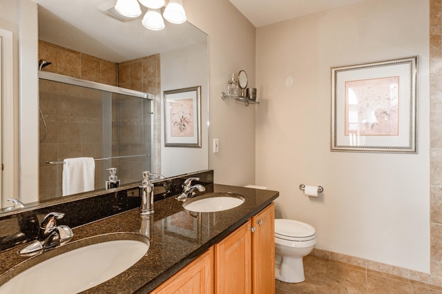 bathroom with toilet, a stall shower, double vanity, and a sink