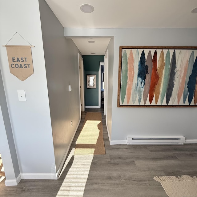 hallway featuring baseboards, baseboard heating, and wood finished floors