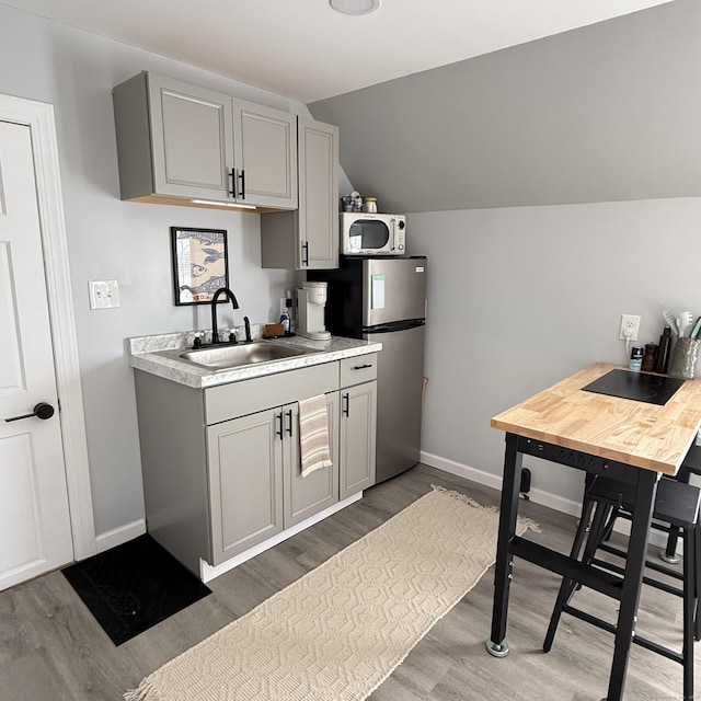kitchen with light countertops, appliances with stainless steel finishes, gray cabinets, and a sink