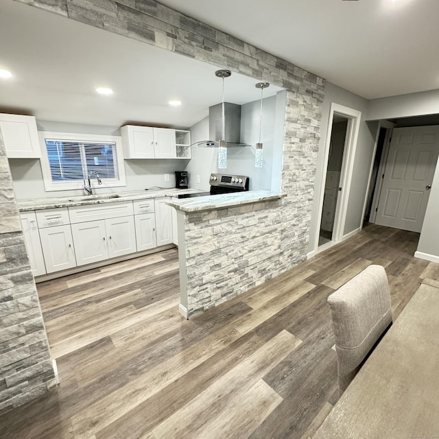 kitchen with wall chimney exhaust hood, light wood-style flooring, a sink, and white cabinetry