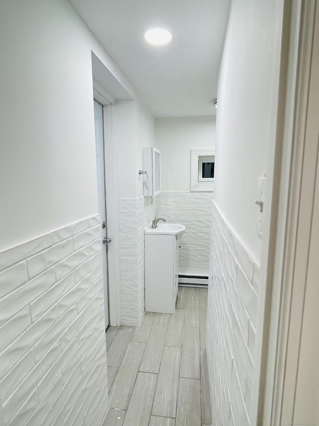 bathroom featuring a wainscoted wall, vanity, and baseboard heating