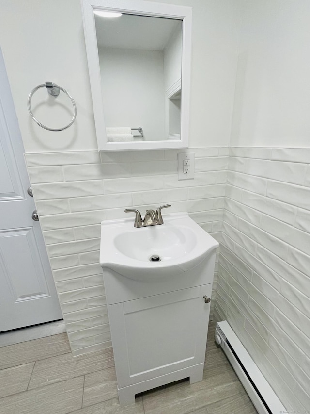 bathroom featuring wainscoting, tile walls, baseboard heating, and vanity