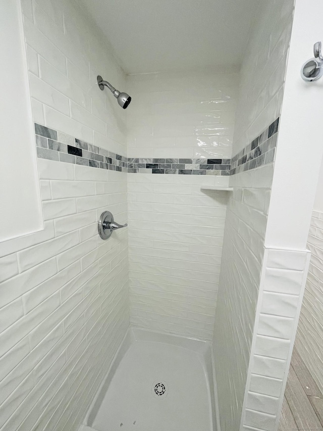 full bath with a tile shower and wainscoting