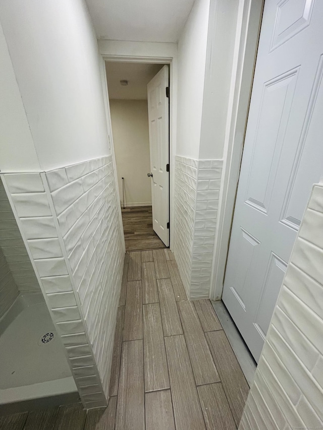 corridor with wainscoting, tile walls, and wood finish floors