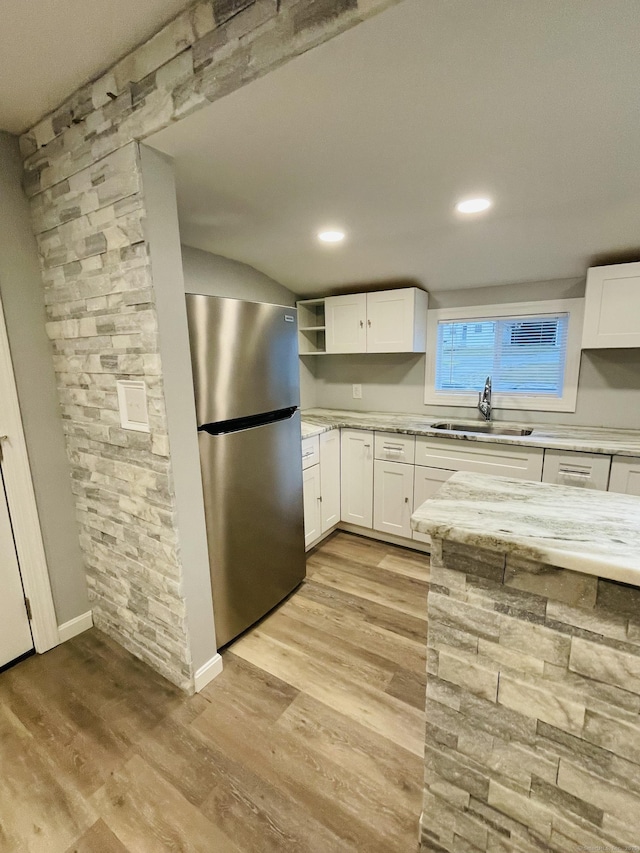 kitchen featuring freestanding refrigerator, light wood-type flooring, white cabinetry, open shelves, and a sink