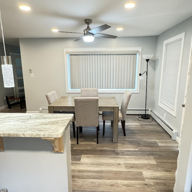 dining room featuring a baseboard radiator, light wood finished floors, and recessed lighting