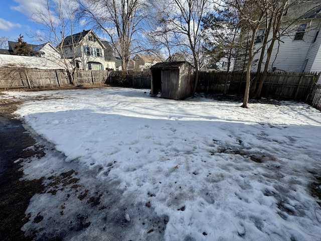 yard covered in snow with an outbuilding, a fenced backyard, and a shed