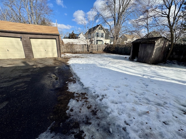 snowy yard with an outbuilding, a storage unit, and fence