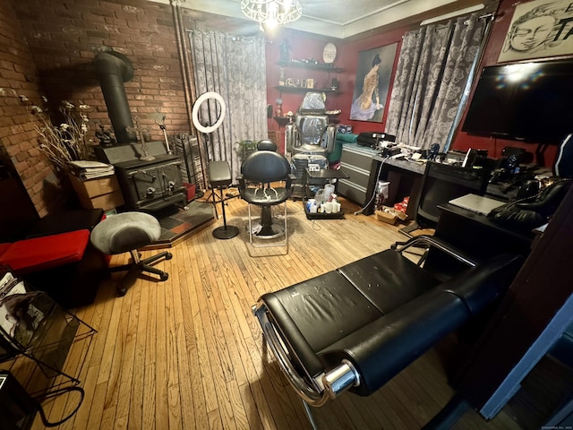 living area featuring brick wall, hardwood / wood-style floors, and a wood stove