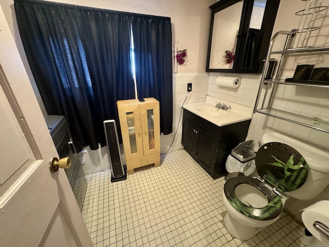 half bath featuring tile patterned flooring, toilet, vanity, tile walls, and wainscoting