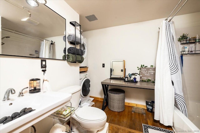 full bathroom featuring toilet, a sink, wood finished floors, shower / tub combo with curtain, and washer / clothes dryer