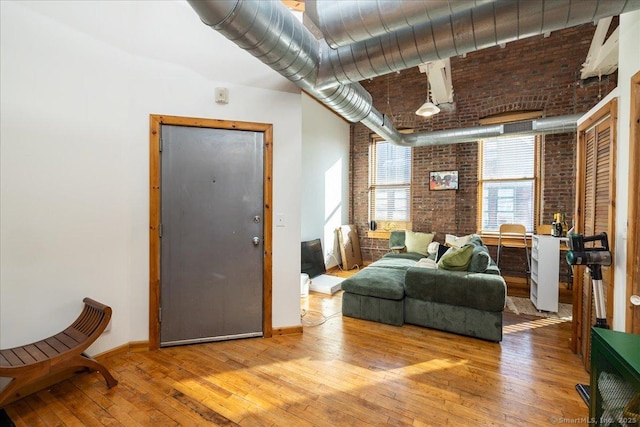 interior space featuring wood-type flooring, baseboards, and brick wall