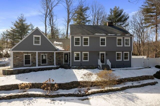 colonial home with a chimney, fence, and a gate