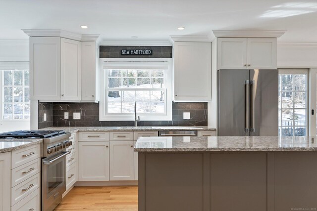 kitchen featuring white cabinetry, a sink, high quality appliances, and crown molding