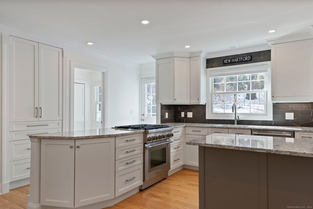 kitchen featuring white cabinets, ornamental molding, stainless steel appliances, and a sink