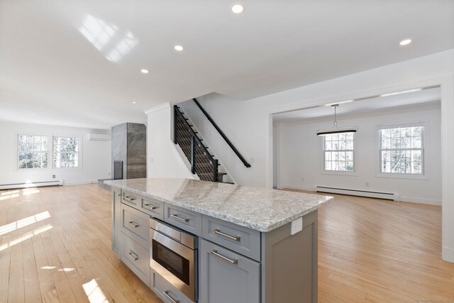 kitchen featuring a baseboard heating unit, open floor plan, gray cabinets, stainless steel microwave, and plenty of natural light