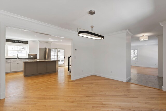 interior space featuring light wood-style flooring, a kitchen island, ornamental molding, and freestanding refrigerator