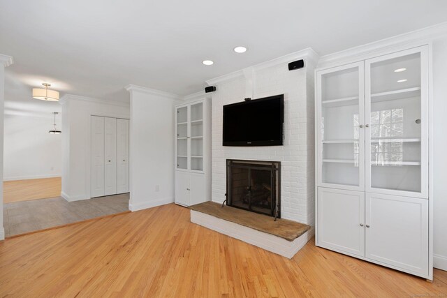 unfurnished living room featuring a fireplace, recessed lighting, light wood-style floors, ornamental molding, and baseboards