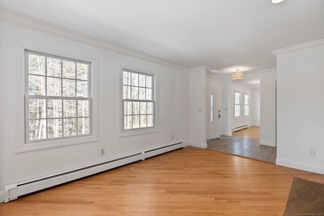 unfurnished room featuring light wood-style floors, baseboards, ornamental molding, and baseboard heating