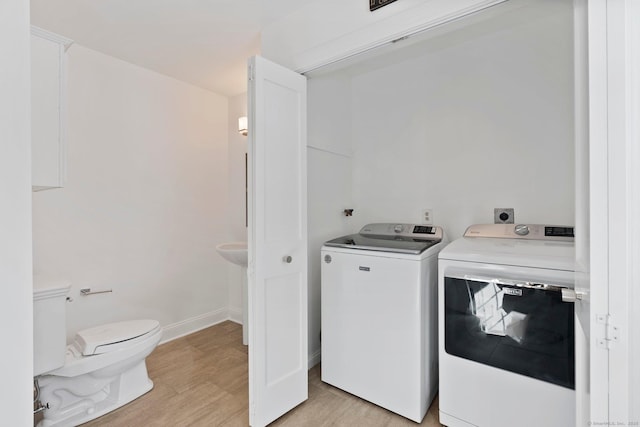 laundry area featuring baseboards, laundry area, washing machine and dryer, and light wood-style floors