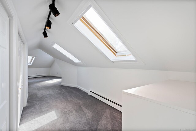 additional living space featuring carpet floors, a baseboard radiator, vaulted ceiling with skylight, and baseboards