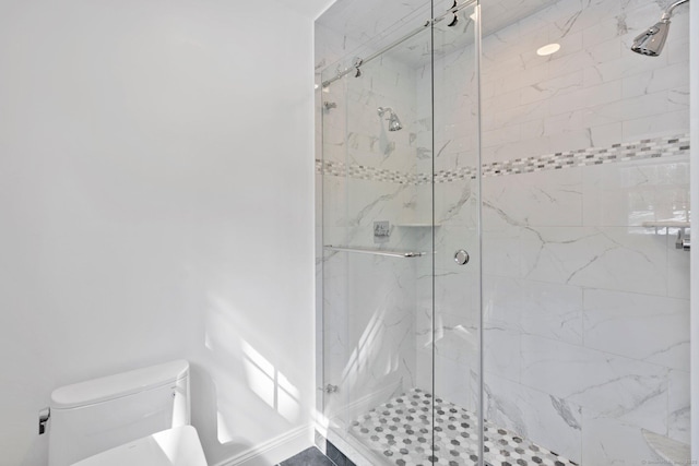 bathroom featuring toilet and a marble finish shower