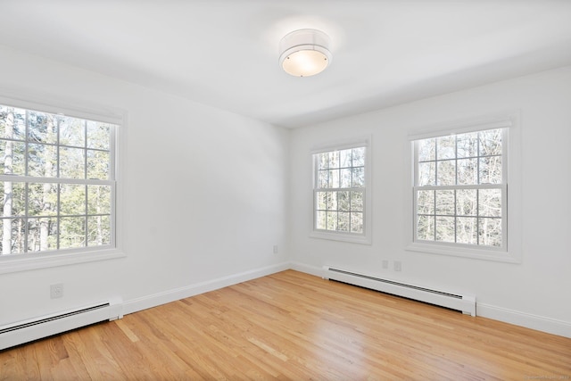 unfurnished room with a baseboard radiator, wood finished floors, and baseboards