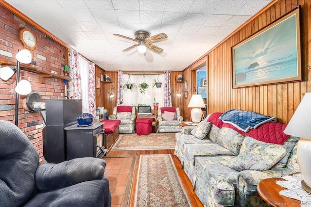 living area with a ceiling fan, wooden walls, brick wall, and wood finished floors